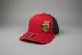 BHT Grooming Co. red front trucker hat with black mesh back and embroidered woodpecker logo.